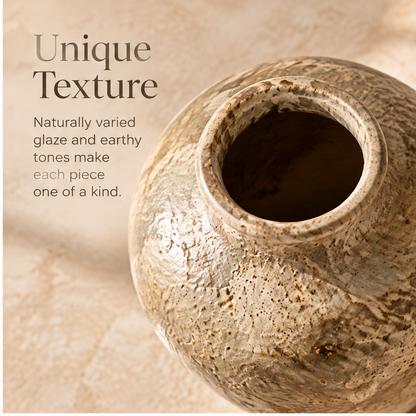 Earth-tone glazed vase styled with leafy decorative branches beside a bowl.